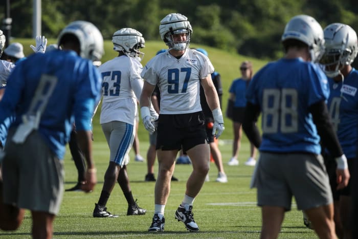 Aidan Hutchinson stands at training camp as players walk around him